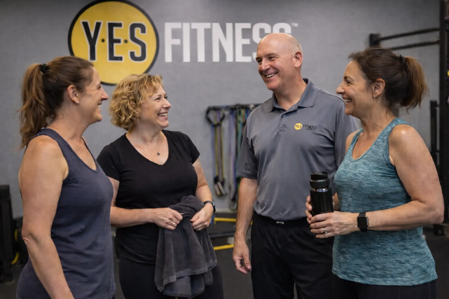 Members and coach laughing together after a group session at YES Fitness